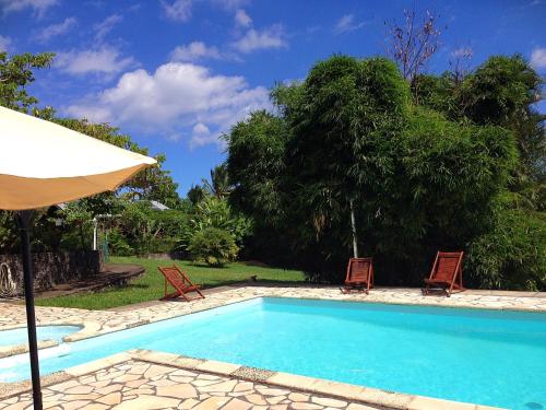 a swimming pool with two chairs and an umbrella at Saint Leu - Chambre 3 épis avec PDJ piscine en pleine nature vue mer - Bardzour in Saint-Leu