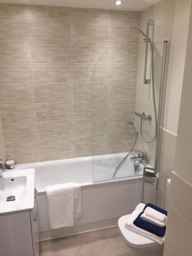 a bathroom with a tub and a toilet and a sink at Portfolio Apartments - Welwyn Business Park in Welwyn Garden City