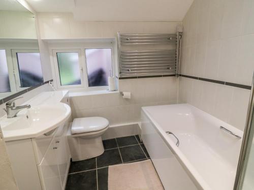 a bathroom with a tub and a toilet and a sink at 2 Rose Cottages in Looe