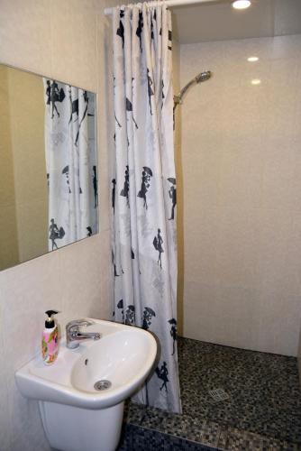 une salle de bain avec un lavabo et un rideau de douche dans l'établissement Sweetdream Hostel, à Kharkov
