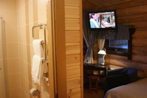 uma casa de banho com televisão e um quarto com cama em Herrfallet em Arboga