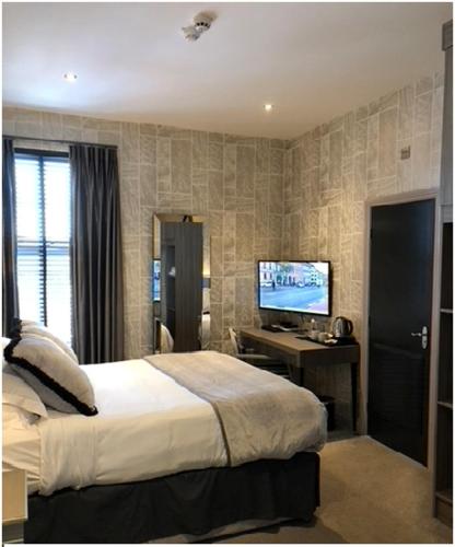 a bedroom with a bed and a desk with a television at The Eccleston Hotel; BW Signature Collection in Saint Helens