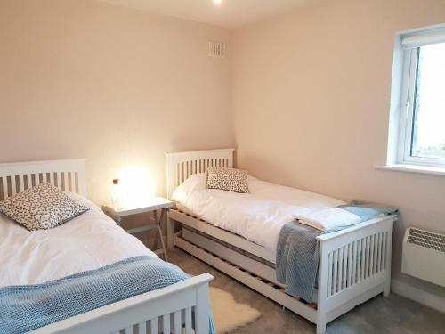 een slaapkamer met 2 bedden en een raam bij Murlach Moorings in Ballyconneely