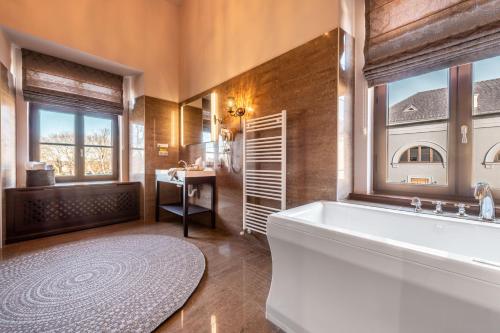 ein großes Bad mit einer Badewanne und einem Fenster in der Unterkunft Chateau Appony in Oponice