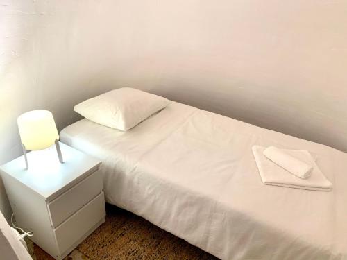 a white bed with two pillows and a night stand at Casa Cueva Castillo in Perales de Tajuña
