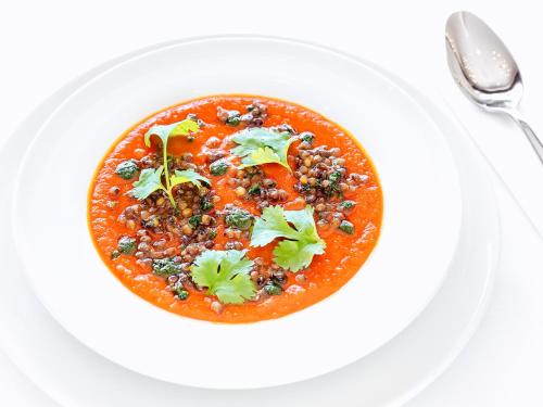 a bowl of soup on a white plate with a spoon at Hotel Woiński Spa in Lubniewice