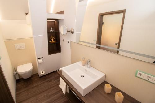 a bathroom with a sink and a toilet and a mirror at Burgschänke, Hotel & Restaurant - E-Mobilität Ladestationen für Elektroautos in Burgthann