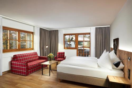 a hotel room with a bed and a red couch at HYPERION Hotel Garmisch - Partenkirchen in Garmisch-Partenkirchen