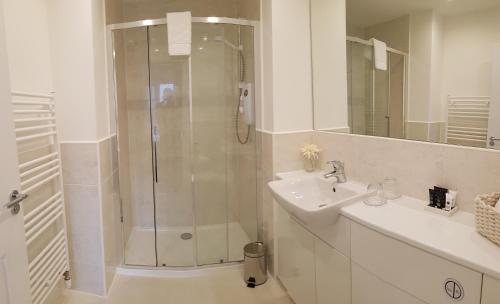 a white bathroom with a shower and a sink at 23 Hedgefield House in Inverness