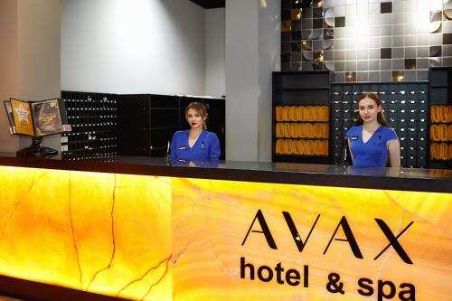 Dos mujeres de pie detrás de un hotel y un mostrador de spa en Grand Spa Hotel Avax en Krasnodar
