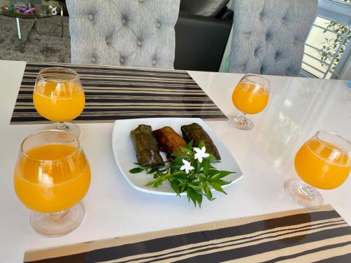 Una mesa con un plato de comida y dos vasos de jugo de naranja. en The Oxygenhomestay @hatyai, en Songkhla