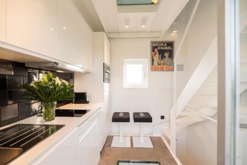 uma cozinha branca com uma escada e um vaso de flores em Logement insolite La tour de Larbuisson em Herve