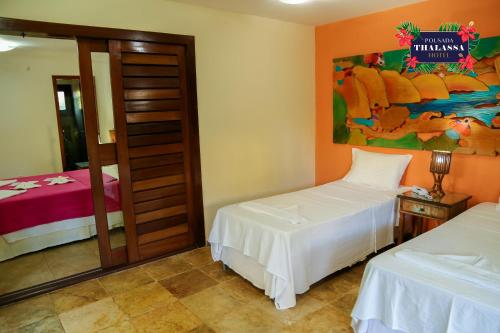 a bedroom with two beds and a painting on the wall at ThalassaGarden Hotel - Pousada in Pipa
