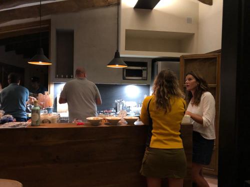 two women standing at a counter in a kitchen at CAL PUIG, ENOTURISMO RURAL entre Viñas y Bosques in Juncosa