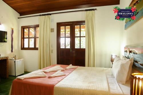 a bedroom with a large bed with a red blanket at ThalassaGarden Hotel - Pousada in Pipa
