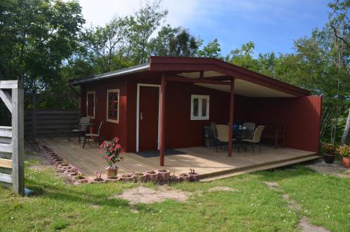 a red cabin with a deck with a table at Klitgaarden in Hjørring