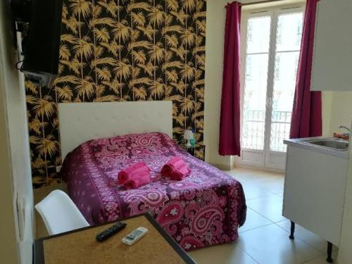 Schlafzimmer mit einem Bett mit rosa Bettwäsche und einem Tisch in der Unterkunft Résidence Pearl in Nizza