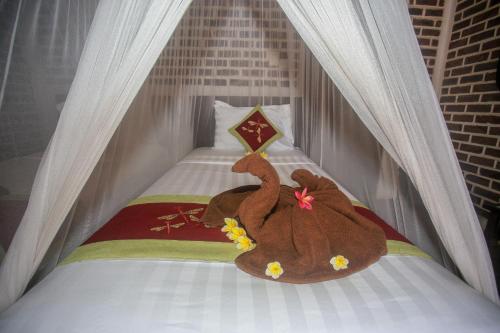 a teddy bear laying on top of a bed at Balangan Sea View Bungalow in Jimbaran