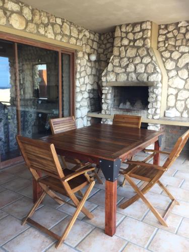 a wooden table and chairs in front of a stone fireplace at Kite View 2 Holiday Home in Witsand