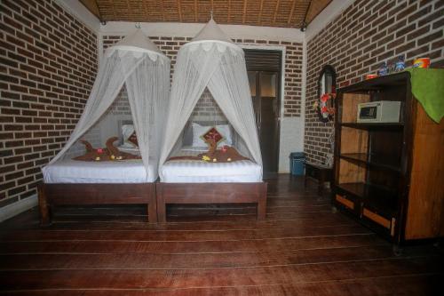 2 camas con cortinas en una habitación con una pared de ladrillo en Balangan Sea View Bungalow en Jimbaran