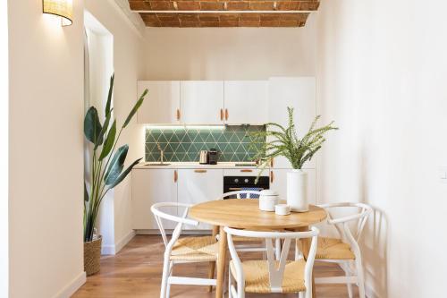 a small kitchen with a wooden table and chairs at Olala Diagonal Apartments in Barcelona