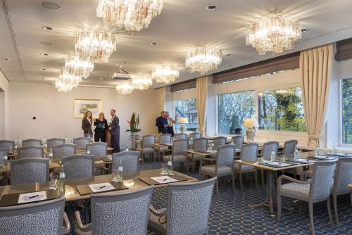 a dining room with tables and chairs and chandeliers at Maritim Hotel Bellevue Kiel in Kiel