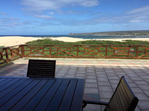 a wooden deck with two benches and a view of the beach at Kite View 2 Holiday Home in Witsand