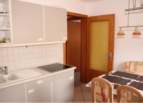 eine Küche mit einem Waschbecken und einem Tisch mit Stühlen in der Unterkunft Ferienwohnung Barbara in Hagenburg