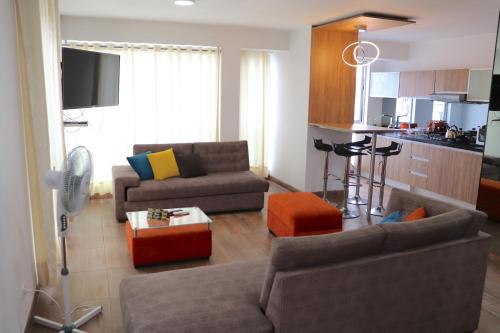 a living room with two couches and a kitchen at Residencial Cafferata in Lima