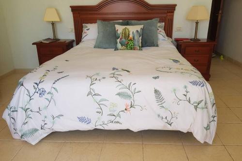 Casa Amber, Los Gigantes, Simply Stunning في Acantilado de los Gigantes: سرير مع لحاف أبيض عليه زهور
