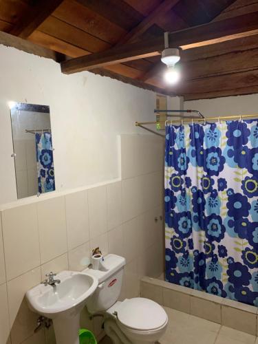 a bathroom with a toilet and a sink and a shower curtain at Candurumy Lodge in Tena