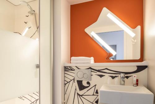 ein Bad mit einem Waschbecken und einem Spiegel in der Unterkunft ibis budget Reims Thillois in Reims