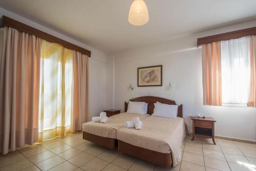 a bedroom with a bed and two windows at Giannoulaki Hotel in M&yacute;konos City