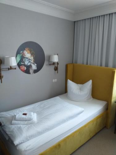 a bedroom with a bed with white sheets and a clock on the wall at Hotel Landgasthof Adler in Bad Krozingen