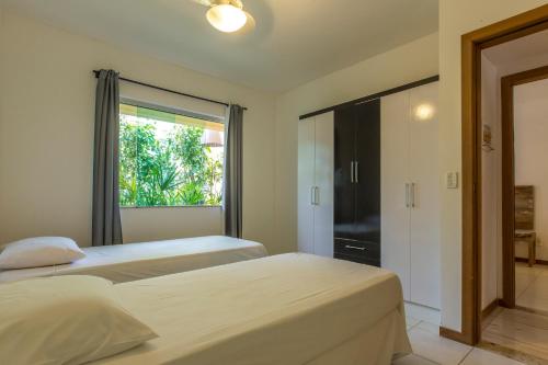 um quarto com 2 camas e uma janela em Apartamento 2 quartos no Imbassai Breezes em Imbassaí