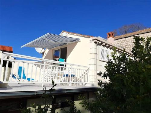 a white house with a balcony with a solarium at Apartments Barbaresko in Lumbarda