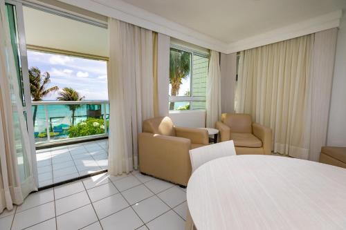 a living room with a table and chairs and a balcony at Hotel Ponta Negra Beach Natal in Natal
