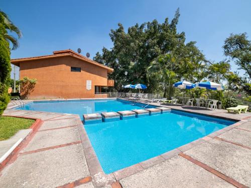 a swimming pool with chairs and umbrellas next to a building at Hotel La Rinconada Santa Fe in Xochitepec