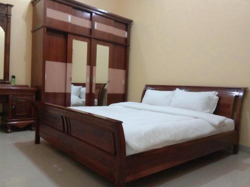 - une chambre avec un grand lit et une tête de lit en bois dans l'établissement Kartika Guest House Cianjur, à Cianjur