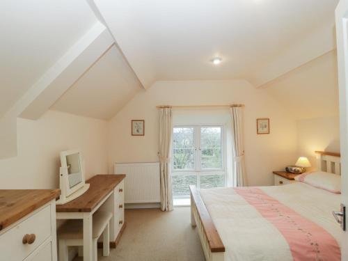 a bedroom with a bed and a desk and a window at Rectory Coach House in Buckhorn Weston