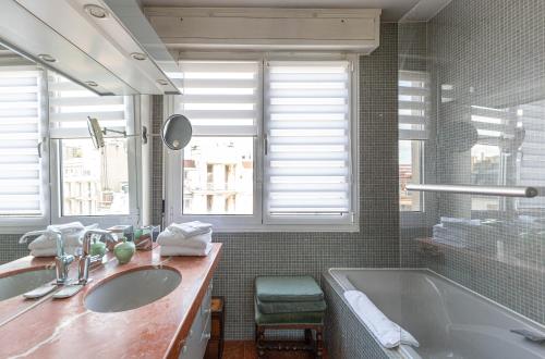 a bathroom with two sinks and a tub and windows at Veeve - Rooftop Views of the Arc de Triomphe in Paris