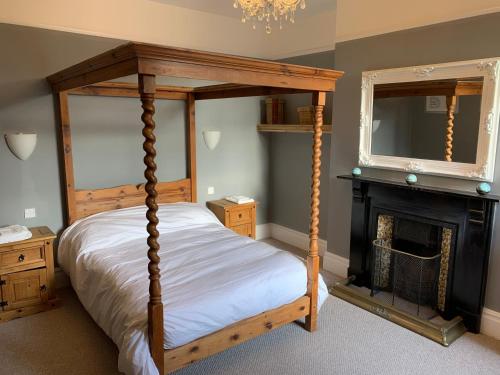 een slaapkamer met een hemelbed en een open haard bij Lansdown House Bed & Breakfast in Market Drayton