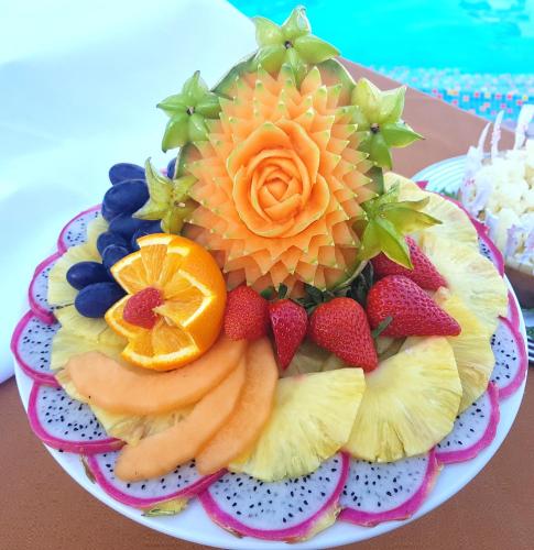 a plate with fruit and flowers on a table at Hotel Mediterraneo in Lignano Sabbiadoro