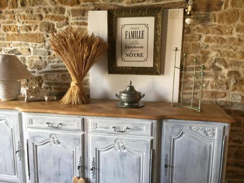 a wooden cabinet with a picture and a vase on top at Chez Mémère Hélène in Sormonne