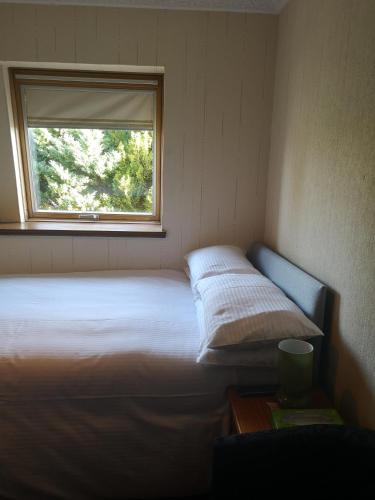 a bed in a small room with a window at Granville Guest House in Dyce