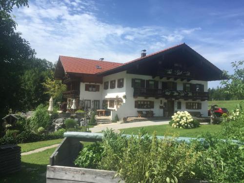 une maison blanche avec un toit rouge dans l'établissement Kienberghof, à Inzell