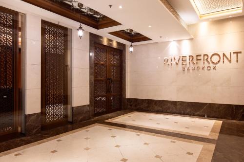 a lobby of a building with a sign on the wall at Riverfront Bangkok in Bangkok