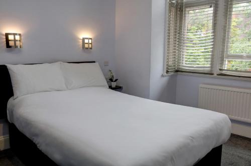 a white bed in a room with two windows at Sure Hotel by Best Western Reading in Reading