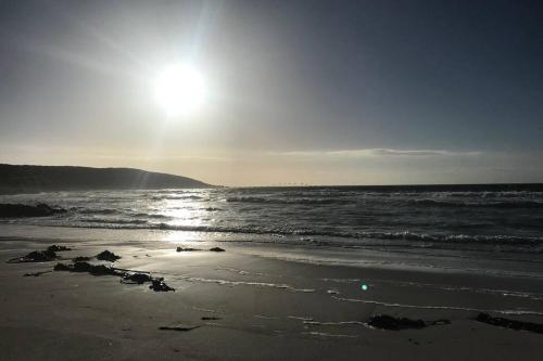 a beach with the sun rising over the ocean at Romansbaai at 402 - with solar power in Gansbaai