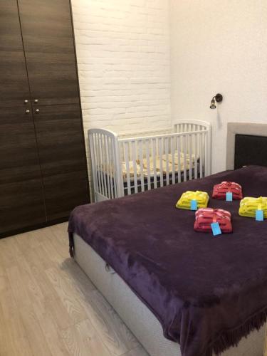 a bedroom with a bed with purple sheets and yellow pillows at Karlsons apartment in Liepāja